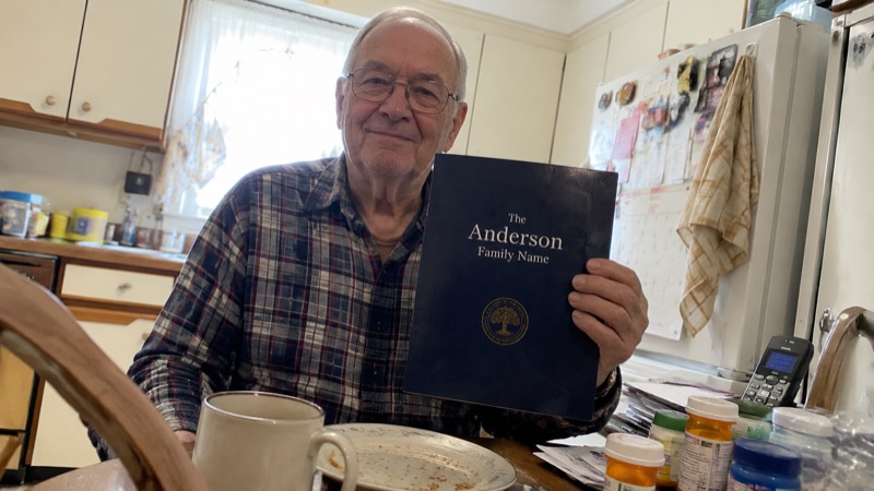Donald Anderson holding his report at the kitchen table